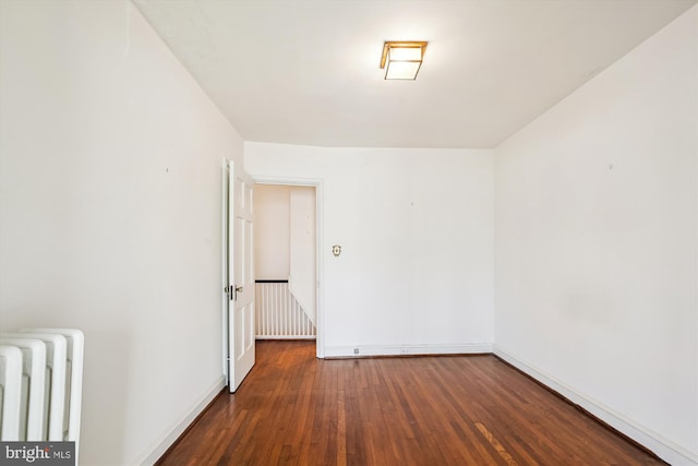 empty room featuring baseboards, radiator heating unit, and wood finished floors