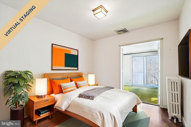 bedroom with access to exterior, radiator heating unit, visible vents, and hardwood / wood-style floors