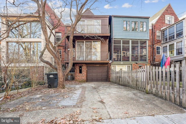 back of house with driveway, an attached garage, fence, cooling unit, and brick siding