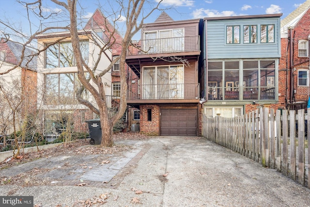 exterior space with brick siding, central AC unit, fence, a garage, and driveway