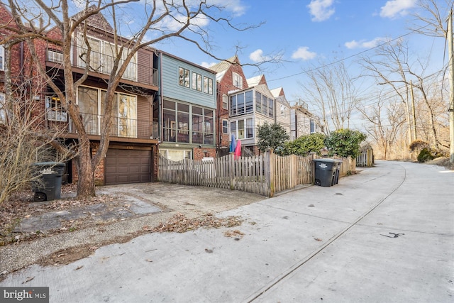 exterior space with a garage, concrete driveway, and fence