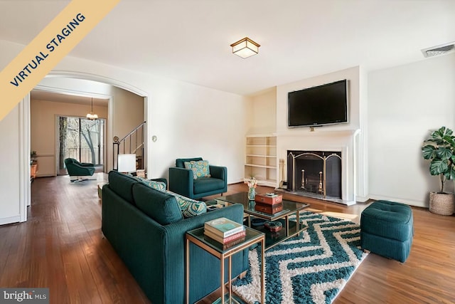 living room with visible vents, arched walkways, hardwood / wood-style flooring, stairway, and a fireplace