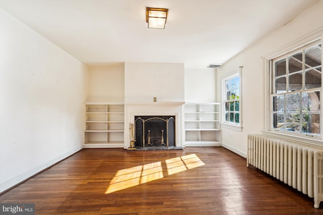 unfurnished living room with radiator, visible vents, a fireplace, and wood-type flooring