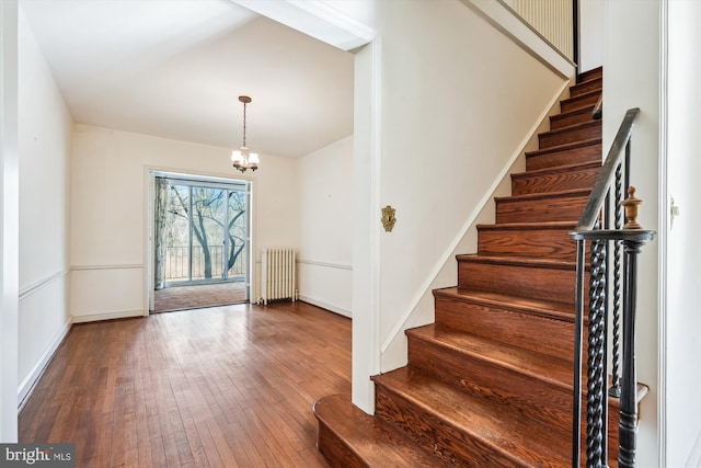 entrance foyer with radiator, baseboards, a chandelier, and hardwood / wood-style floors