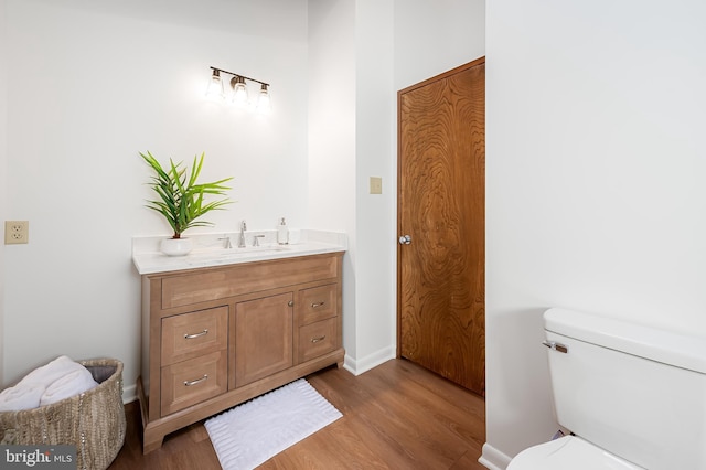 bathroom featuring toilet, vanity, and wood finished floors