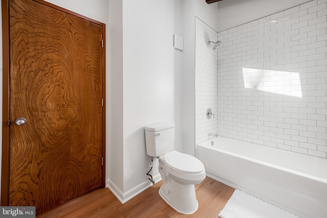 bathroom with bathing tub / shower combination, toilet, and wood finished floors