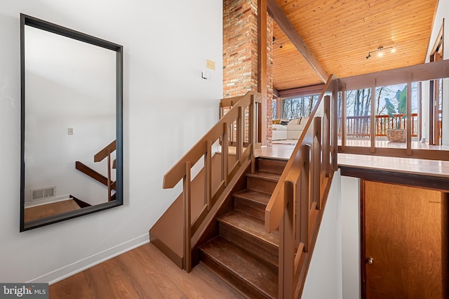 stairs featuring visible vents, baseboards, beamed ceiling, wood ceiling, and wood finished floors