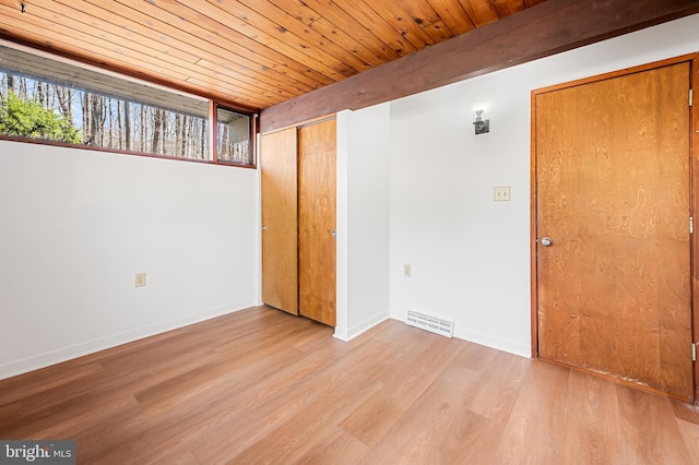 empty room with visible vents, baseboards, wooden ceiling, and light wood finished floors