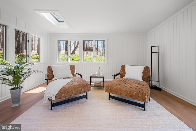 living area featuring baseboards, wood finished floors, and a skylight