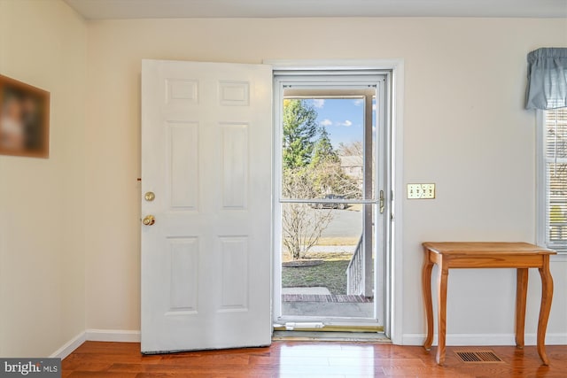 foyer entrance featuring visible vents, baseboards, a healthy amount of sunlight, and wood finished floors