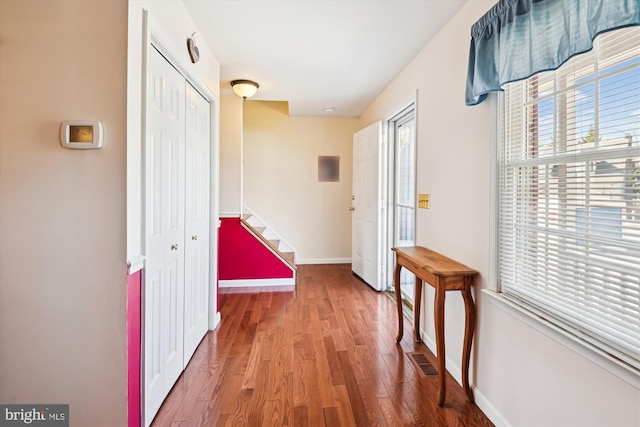 corridor featuring stairs, visible vents, wood finished floors, and baseboards