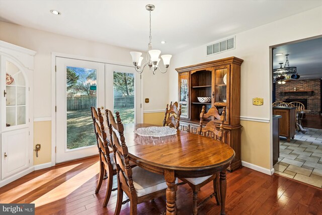 dining area featuring a chandelier, visible vents, a fireplace, and wood-type flooring