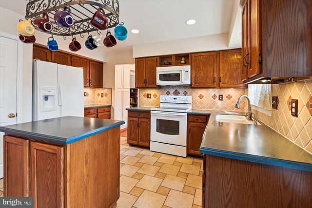 kitchen with dark countertops, decorative backsplash, white appliances, and a sink