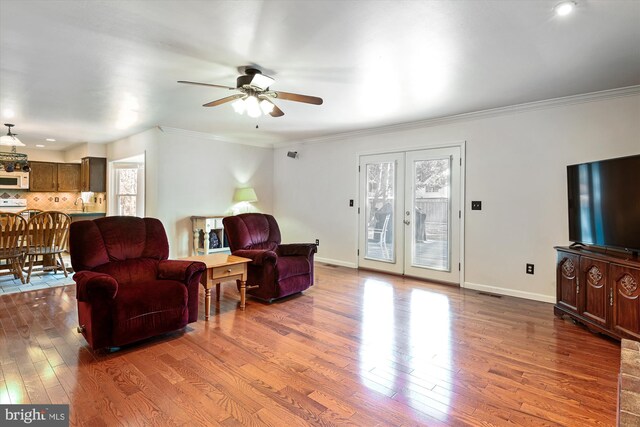 living room featuring wood finished floors, french doors, crown molding, baseboards, and ceiling fan