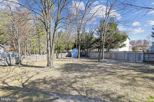 view of yard featuring a fenced backyard, a storage unit, and an outdoor structure