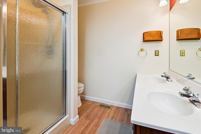 bathroom featuring a sink, baseboards, wood finished floors, and a stall shower