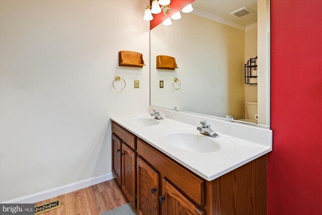 bathroom featuring a sink, visible vents, wood finished floors, and double vanity