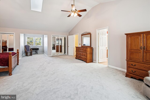 bedroom with a skylight, light colored carpet, baseboards, and high vaulted ceiling