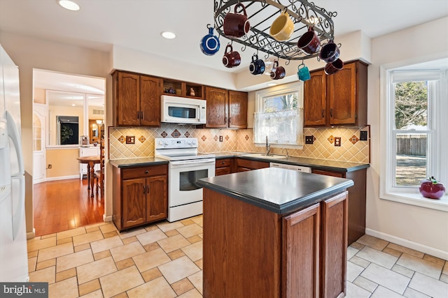 kitchen featuring a sink, decorative backsplash, white appliances, and dark countertops