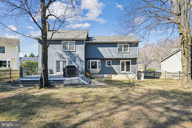 back of house featuring a deck, a lawn, a fenced backyard, and a chimney