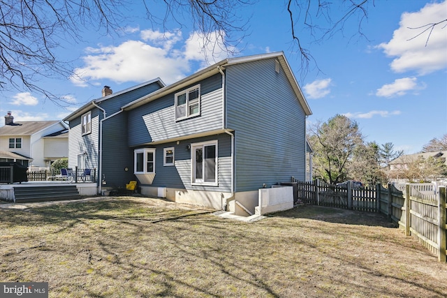 back of property with a lawn, a chimney, and a fenced backyard