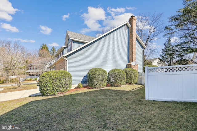 view of property exterior featuring a yard, a chimney, and fence