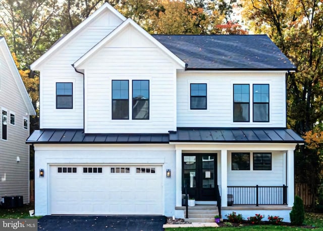 modern farmhouse style home featuring aphalt driveway, central air condition unit, an attached garage, a standing seam roof, and metal roof