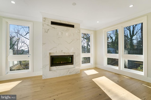 unfurnished living room featuring ornamental molding, a premium fireplace, and light wood-style floors