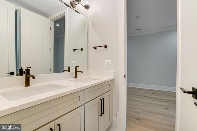 full bath with double vanity, wood finished floors, a sink, and baseboards