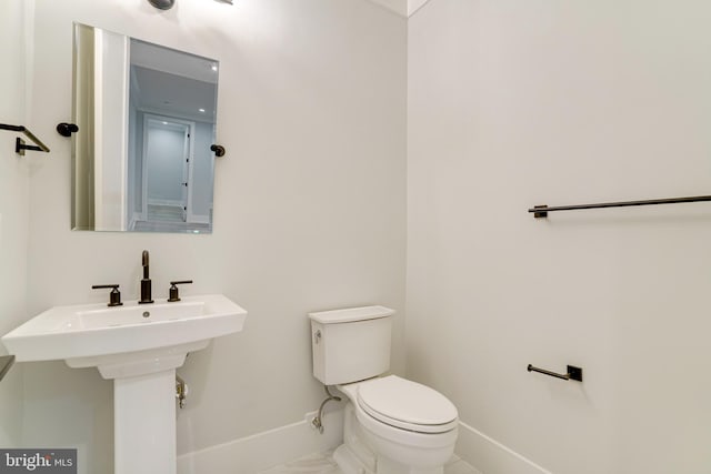 bathroom with marble finish floor, baseboards, a sink, and toilet