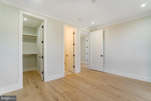 unfurnished bedroom with baseboards, a spacious closet, light wood finished floors, and recessed lighting