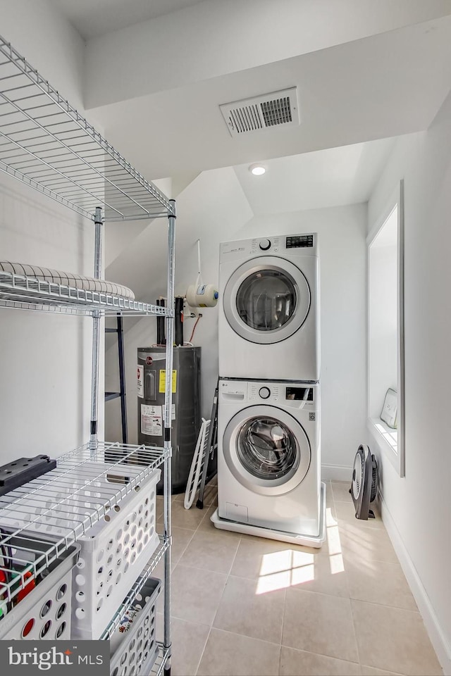 clothes washing area featuring laundry area, visible vents, stacked washer / dryer, water heater, and light tile patterned flooring