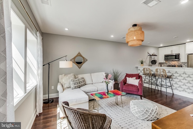 living room with a healthy amount of sunlight, visible vents, dark wood-style flooring, and recessed lighting