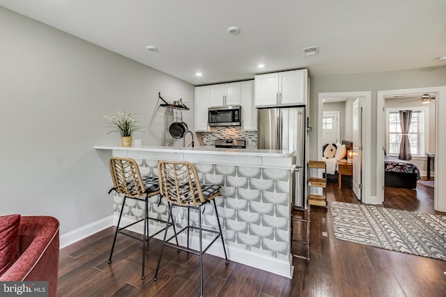 kitchen with stainless steel appliances, visible vents, white cabinetry, light countertops, and dark wood finished floors