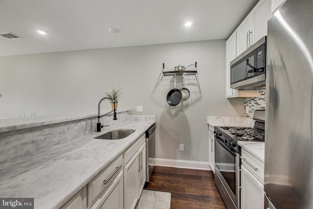 kitchen featuring visible vents, white cabinets, appliances with stainless steel finishes, light stone countertops, and a sink