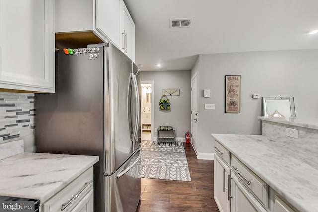 kitchen with dark wood-style floors, visible vents, freestanding refrigerator, white cabinets, and light stone countertops