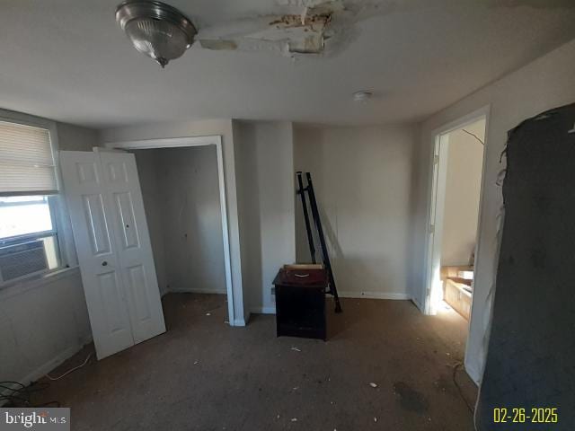 unfurnished bedroom with cooling unit and baseboards