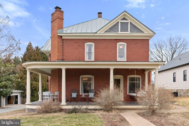 view of front of property with a porch, a standing seam roof, brick siding, and metal roof