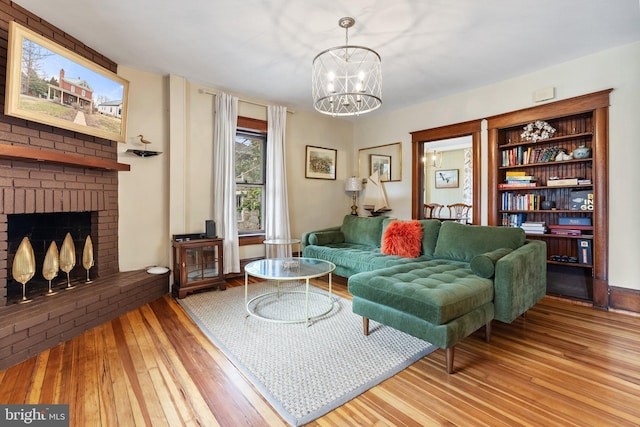 living area featuring a brick fireplace, an inviting chandelier, and wood finished floors