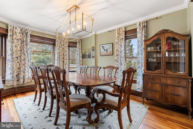 dining space featuring light wood finished floors, ornamental molding, and a chandelier