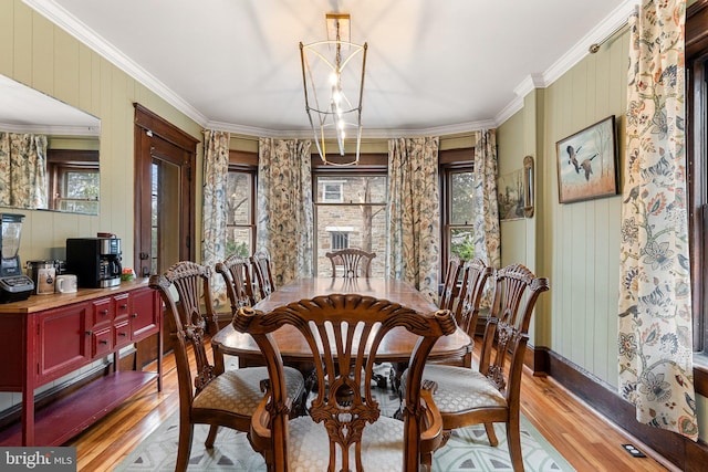 dining space featuring light wood-type flooring, an inviting chandelier, baseboards, and ornamental molding