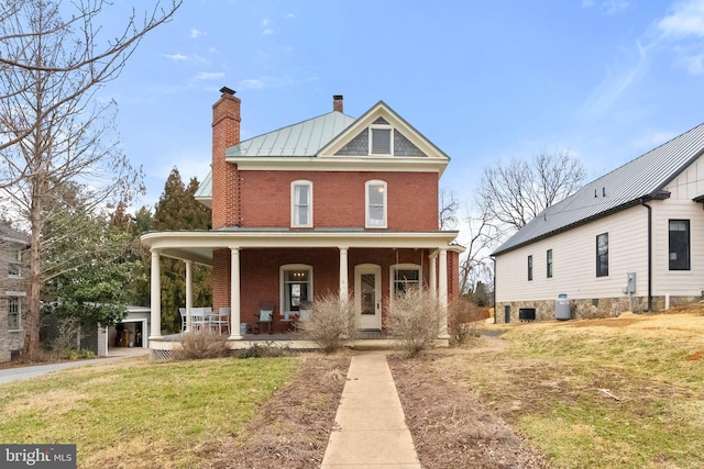 view of front of property with brick siding, a chimney, a porch, a standing seam roof, and metal roof