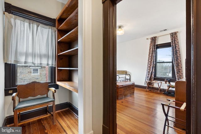 sitting room with baseboards, visible vents, and wood finished floors