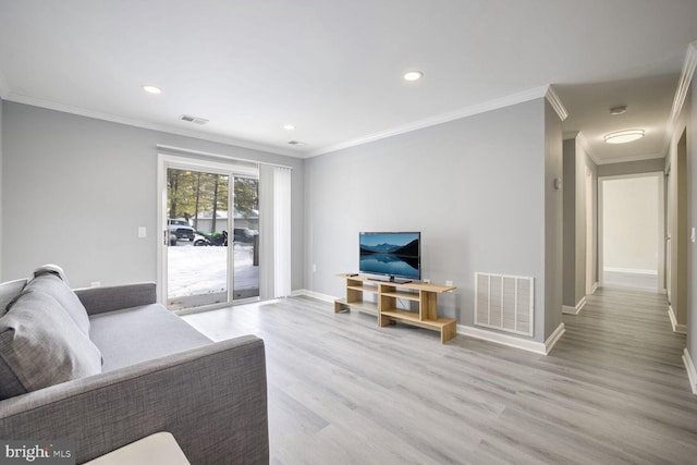 living room with light wood-type flooring, visible vents, crown molding, and baseboards