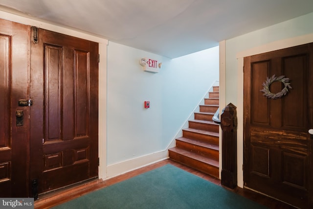 foyer entrance featuring stairway, baseboards, and wood finished floors