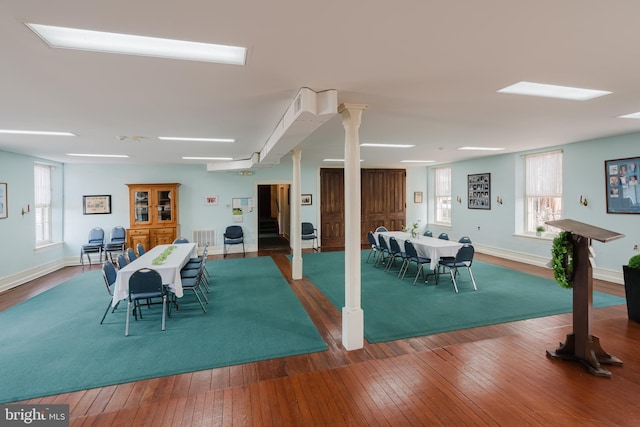 dining area with baseboards, ornate columns, hardwood / wood-style flooring, and a healthy amount of sunlight