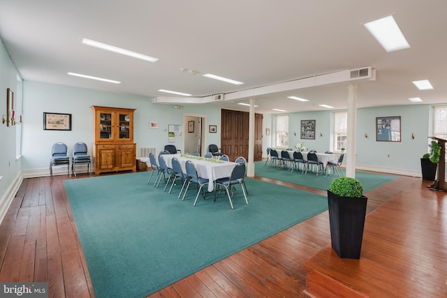 dining space with wood-type flooring, visible vents, and baseboards