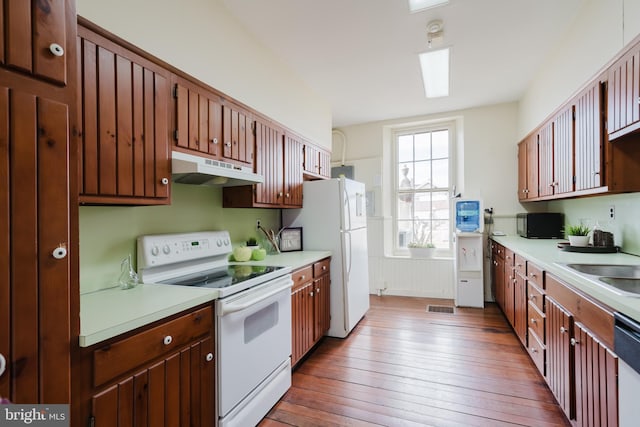 kitchen featuring light countertops, white appliances, hardwood / wood-style floors, and under cabinet range hood