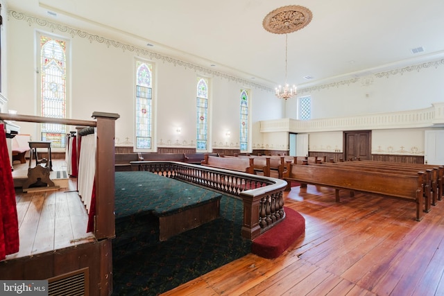 recreation room with a wainscoted wall, wood-type flooring, visible vents, and a notable chandelier