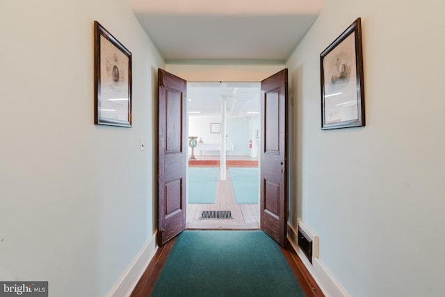 doorway to outside featuring dark wood-style flooring, visible vents, and baseboards